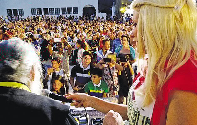 ΚΟΣΜΟΣΥΡΡΟΗ • Η παρουσιάστρια κρατά το μικρόφωνο για να μιλήσει στον κόσμο ο μοναχός