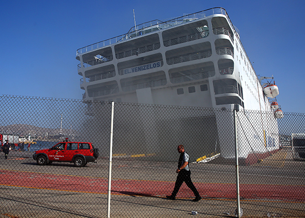 Καμένο φορτηγό με φόντο το πλοίο που έχει πάρει κλίση