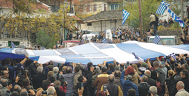 Η τεράστια ελληνική σημαία σκεπάζει τη σορό και την οδηγεί στο κοιμητήριο του χωριού