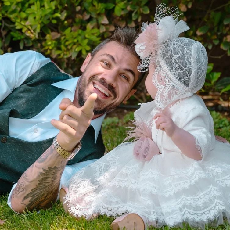 Photo by Akis Petretzikis on May 07 2023. May be an image of 2 people beard baby people smiling bow flower outdoors and