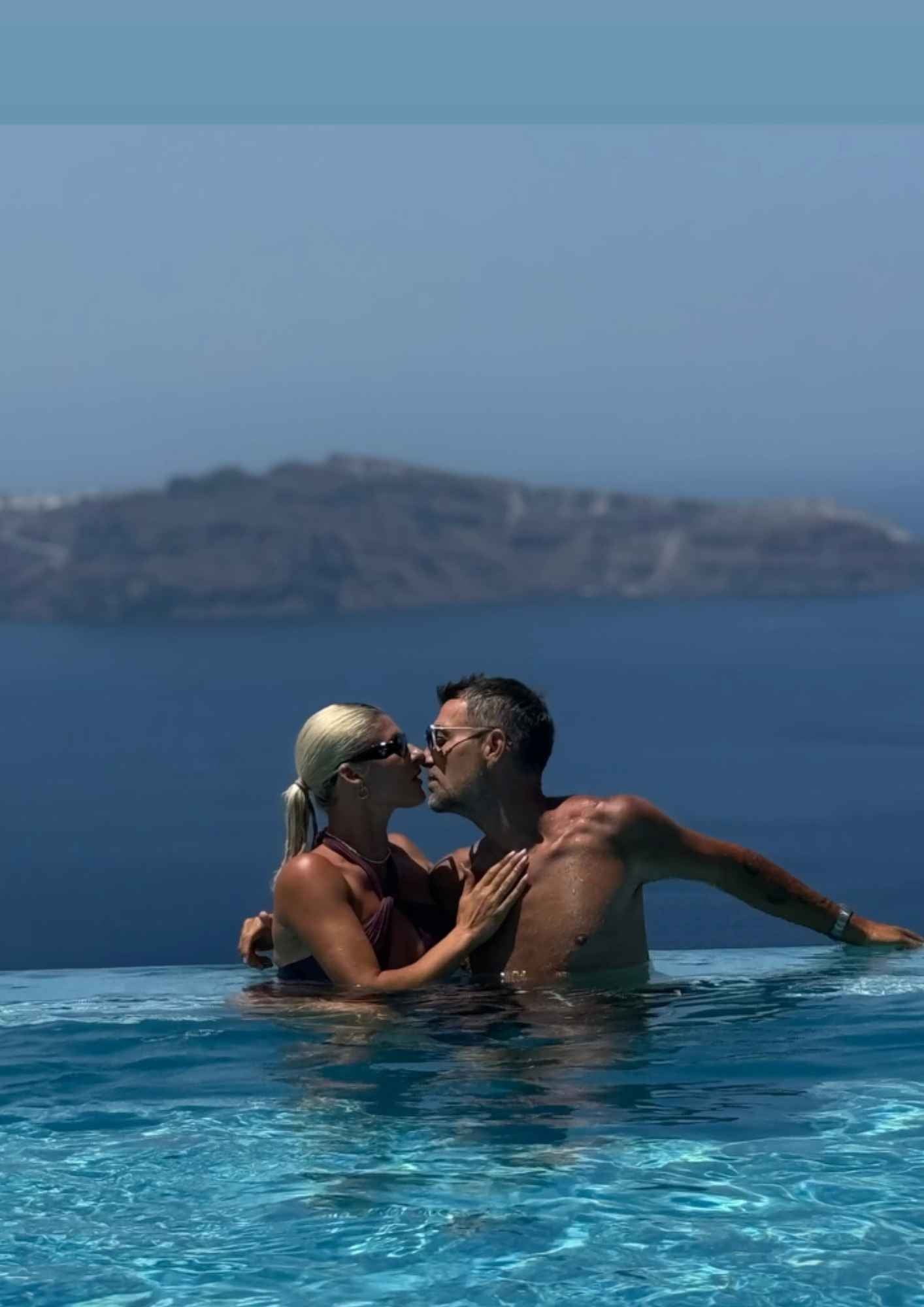 Ο Στέλιος Χανταμπάκης και η Όλγα Πηλιάκη ανταλλάσσουν ένα τρυφερό φιλί με θέα την Καλντέρα.